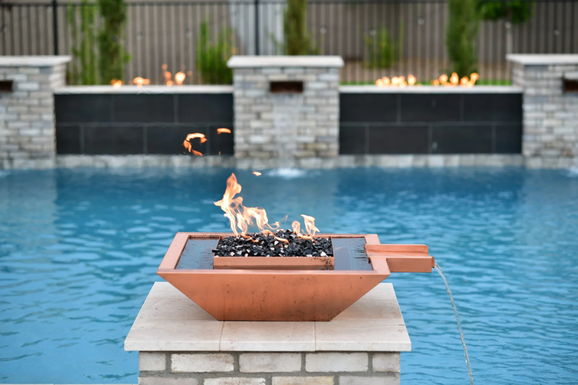 Copper fire and water bowl on a stone column in a blue pool